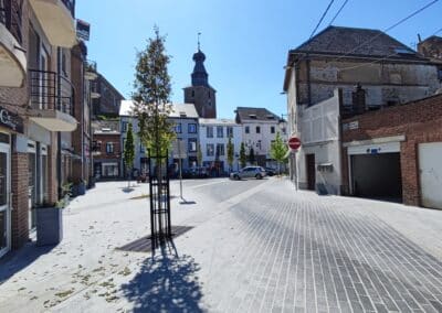Vue de la Place de l'Orneau, un espace central de Gembloux, avec ses commerces et son ambiance animée.