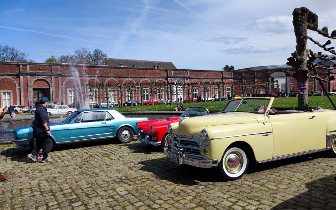 Vieille voiture Auto Rétro à Gembloux, avec des véhicules jaunes, rouges et bleus, créant un ensemble coloré et vintage dans un cadre pittoresque.