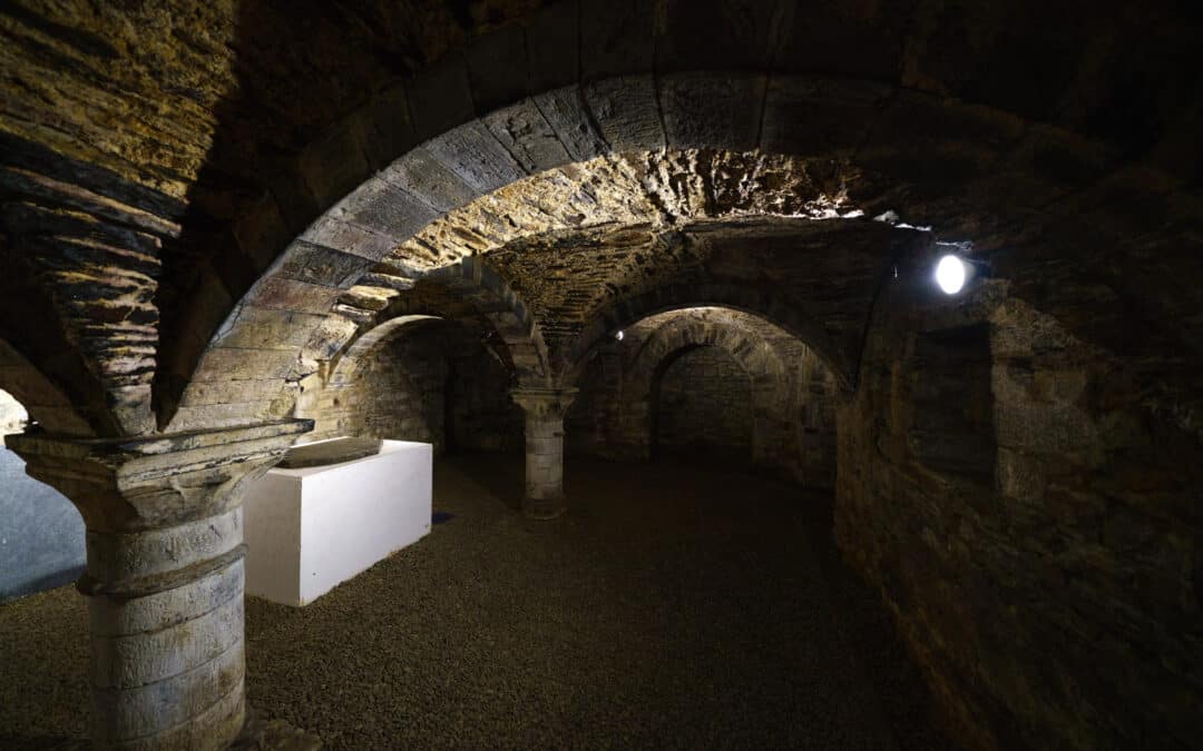 Intérieur de la crypte à Gembloux, dévoilant une atmosphère mystérieuse et historique, avec ses voûtes, ses pierres anciennes et ses éléments architecturaux remarquables.